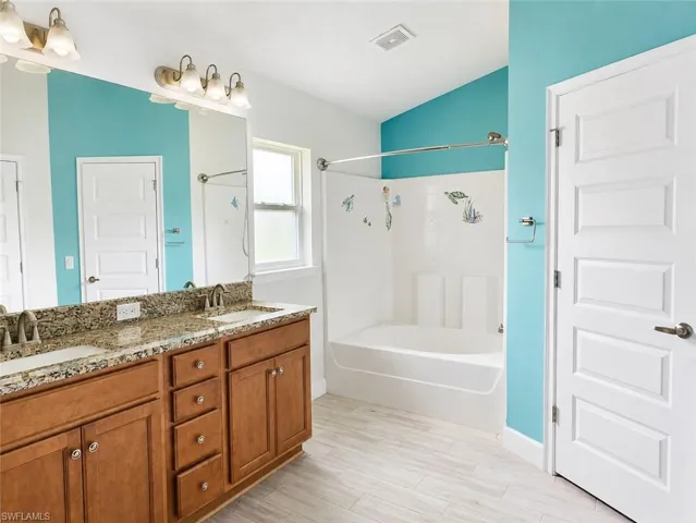 Double vanity with stone countertop, dual undermount sinks, and wood-finish cabinetry