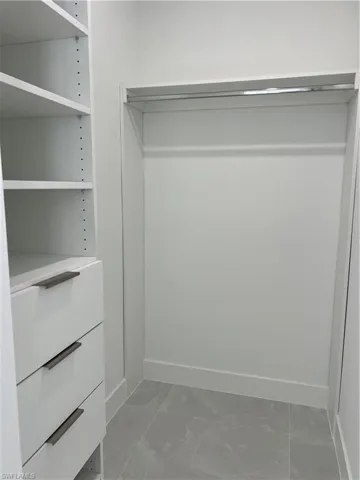 Walk in closet with light marble finish flooring