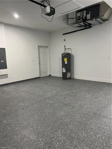 Garage featuring water heater, a garage door opener, and electric panel