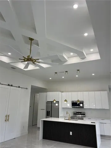 Kitchen featuring stove, refrigerator, recessed lighting, white cabinets, and light countertops
