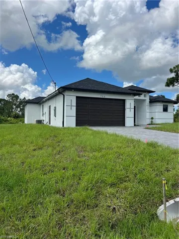 View of front facade with an attached garage, stucco siding, a front yard, and driveway
