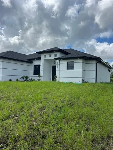 View of front facade with stucco siding and roof with shingles