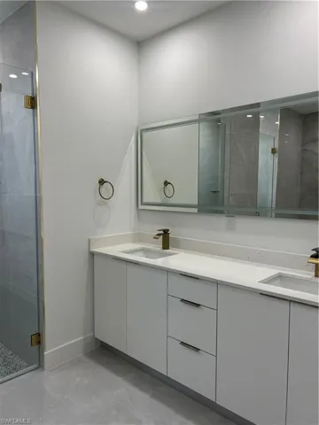 Full bath with double vanity, a stall shower, marble finish flooring, and recessed lighting
