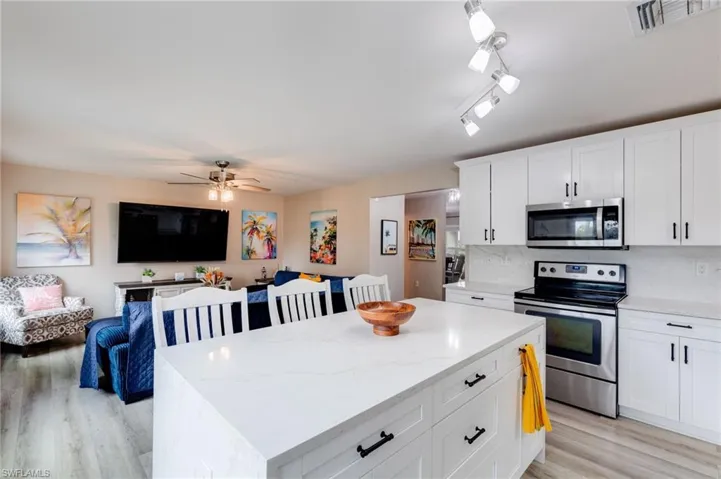 Kitchen with stainless steel appliances, open floor plan, white cabinets, and a kitchen island