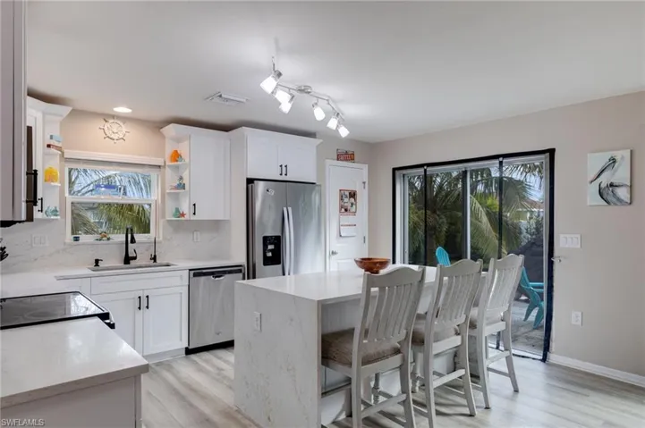 Kitchen with light stone countertops, appliances with stainless steel finishes, a breakfast bar area, and backsplash