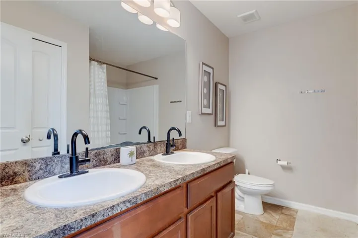 Full bathroom featuring double vanity, a shower with curtain, and light tile patterned flooring
