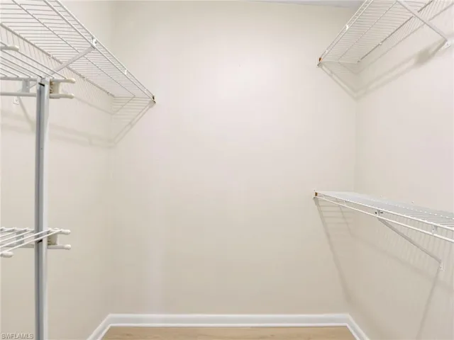 Walk in closet with hardwood / wood-style floors