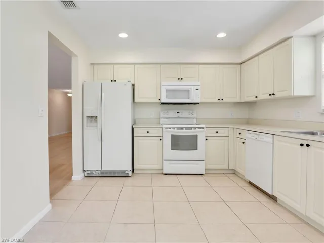 Kitchen with sink, white appliances, and light tile patterned floors