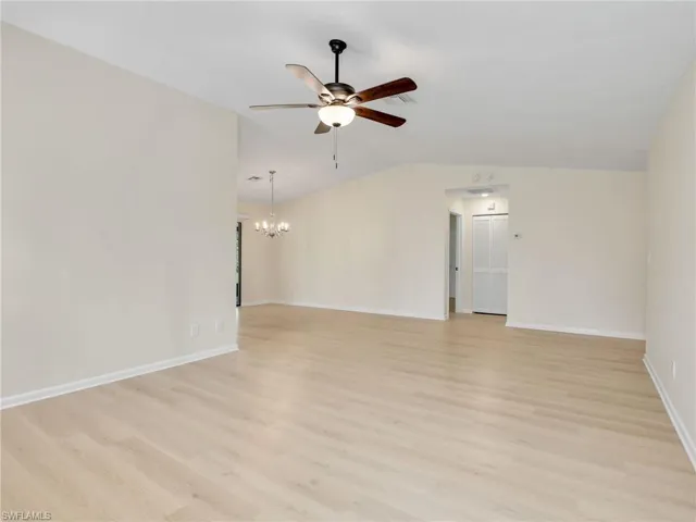 Unfurnished room featuring ceiling fan with notable chandelier, lofted ceiling, and light hardwood / wood-style floors