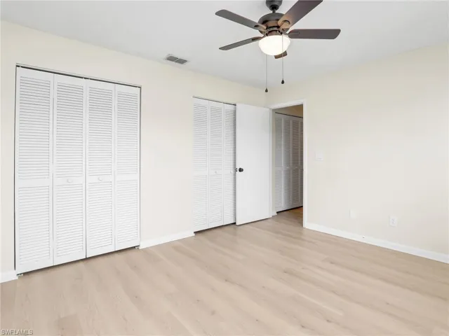 Unfurnished bedroom featuring light hardwood / wood-style floors, multiple closets, and ceiling fan