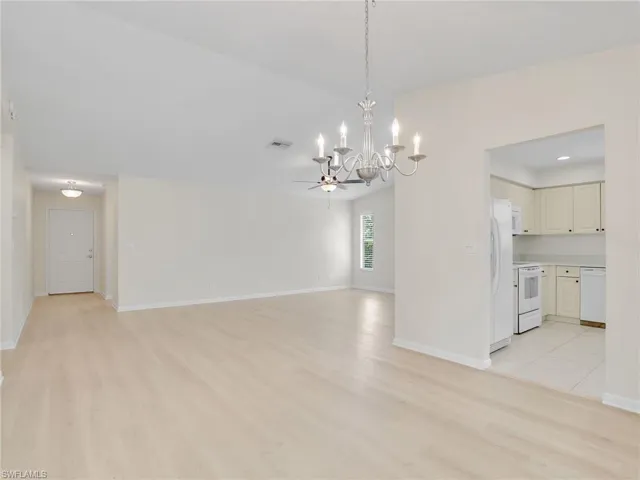 Unfurnished room with ceiling fan with notable chandelier and light hardwood / wood-style floors