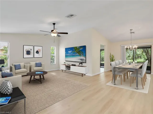 Living room featuring light hardwood / wood-style floors, ceiling fan with notable chandelier, and vaulted ceiling