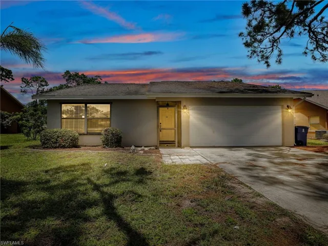 Ranch-style home with a garage and a yard