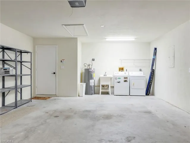 Garage with electric water heater, a garage door opener, washer and dryer, and sink