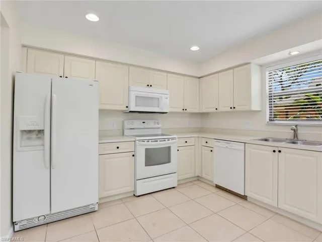 Kitchen featuring sink, white appliances, and light tile patterned floors