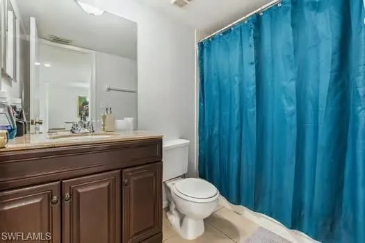 Bathroom featuring toilet, vanity, tile patterned floors, and a shower with shower curtain