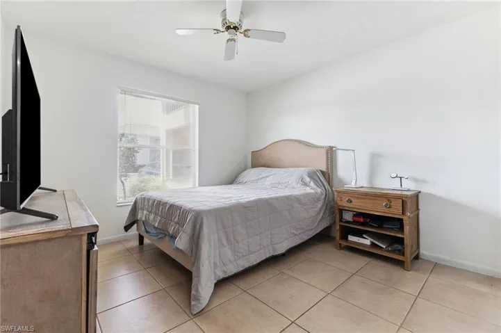 Bedroom with light tile patterned flooring, baseboards, and ceiling fan