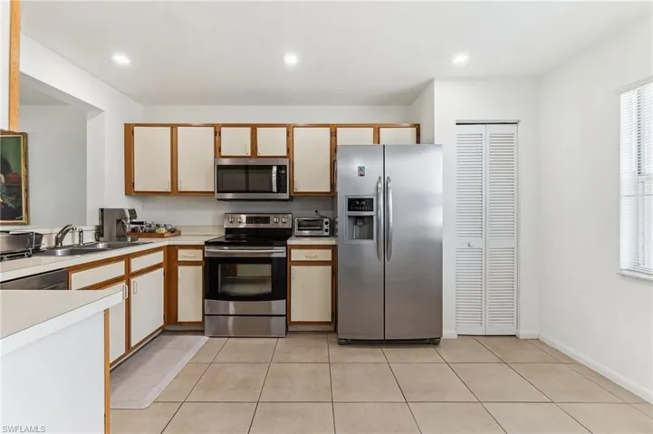 Kitchen featuring light countertops, light tile patterned floors, stainless steel appliances, and a sink