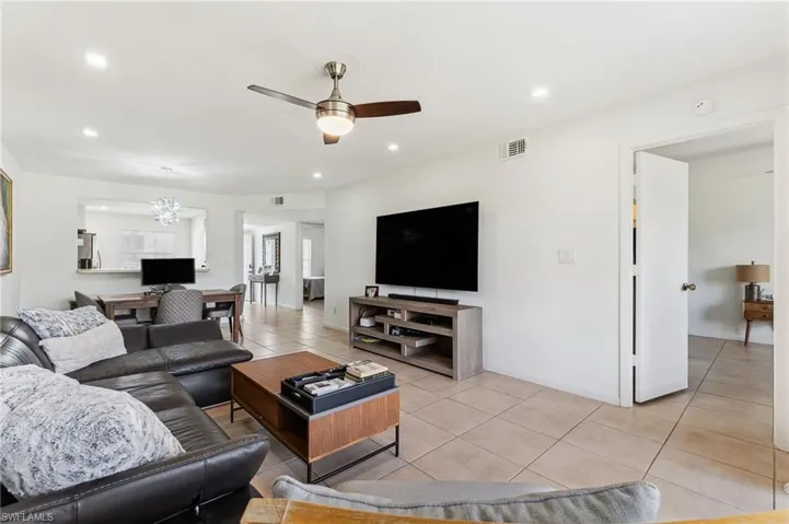 Living room with recessed lighting, visible vents, light tile patterned floors, baseboards, and ceiling fan with notable chandelier