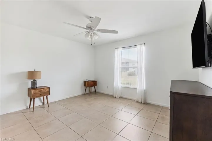 Spare room with light tile patterned flooring, a ceiling fan, and baseboards