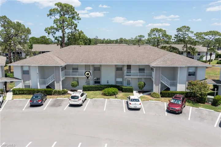 View of property with uncovered parking and stairs