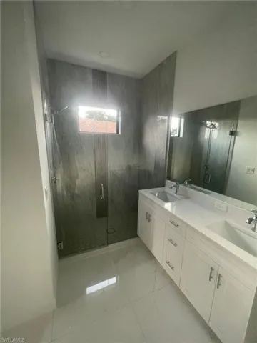 Bathroom with dual vanity, walk in shower, and tile patterned flooring