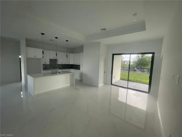 Kitchen with white cabinetry, tasteful backsplash, light tile patterned floors, a raised ceiling, and sink