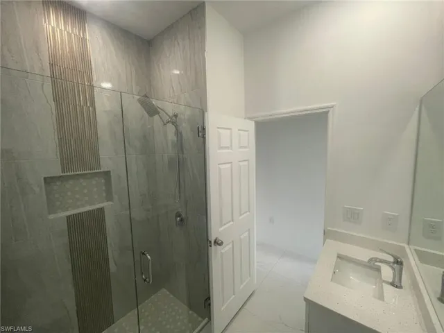 Bathroom featuring a shower with shower door, vanity, and tile patterned flooring