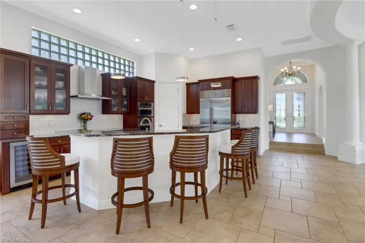 Kitchen featuring appliances with stainless steel finishes, wall chimney exhaust hood, an island with sink, and a wealth of natural light