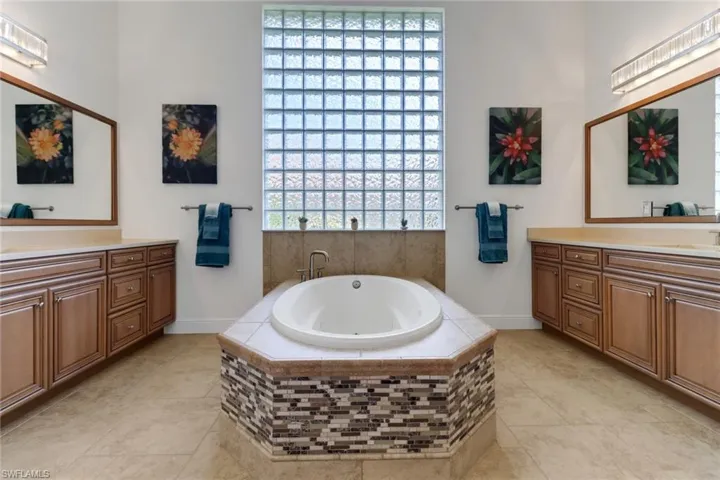 Bathroom featuring vanity, tiled bath, and tile patterned floors