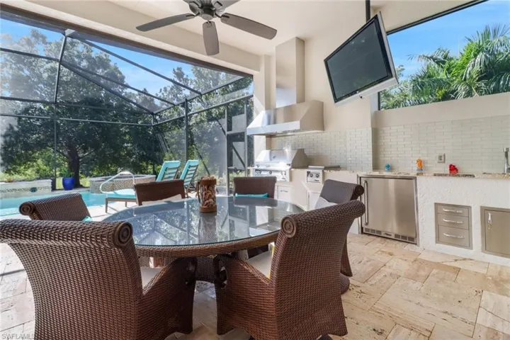 View of patio with a grill, area for grilling, glass enclosure, and ceiling fan