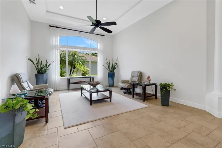 Sitting room with decorative columns, a raised ceiling, and ceiling fan