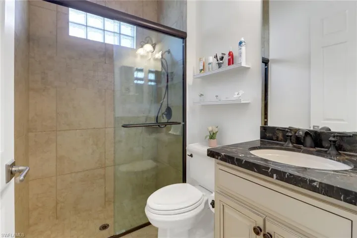 Bathroom featuring a shower with door, vanity, and toilet