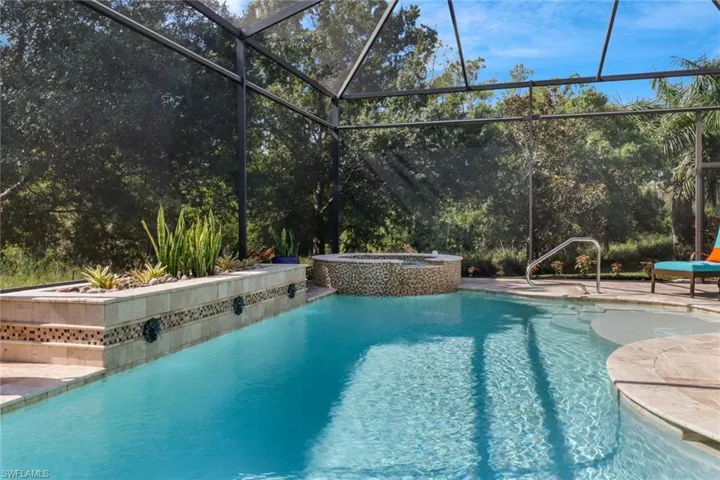 View of pool with an in ground hot tub and glass enclosure