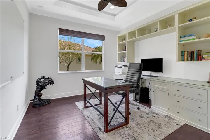 Home office featuring crown molding, a tray ceiling, dark hardwood / wood-style floors, and ceiling fan