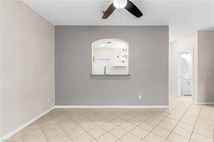 Empty room with light tile patterned floors and a ceiling fan