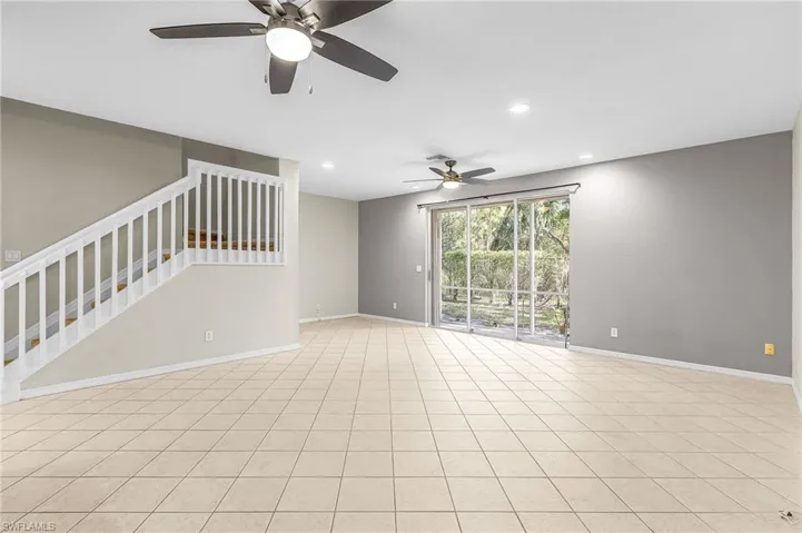 Unfurnished living room featuring recessed lighting, ceiling fan, and stairway