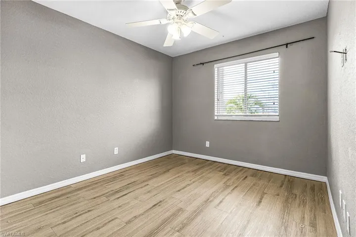 Spare room featuring a textured wall, light wood-style flooring, and ceiling fan