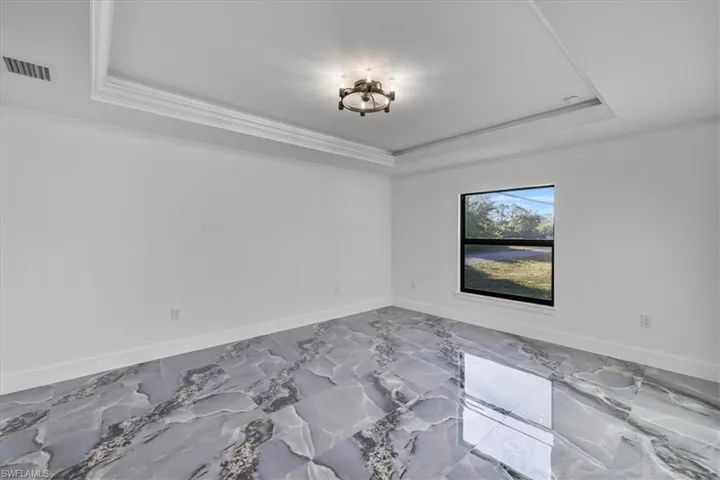 Master bedroom with a raised ceiling and marble tiled floors