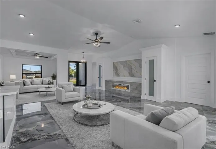 Living area with dark marble finish floors, recessed lighting, a glass covered fireplace, and ceiling fan