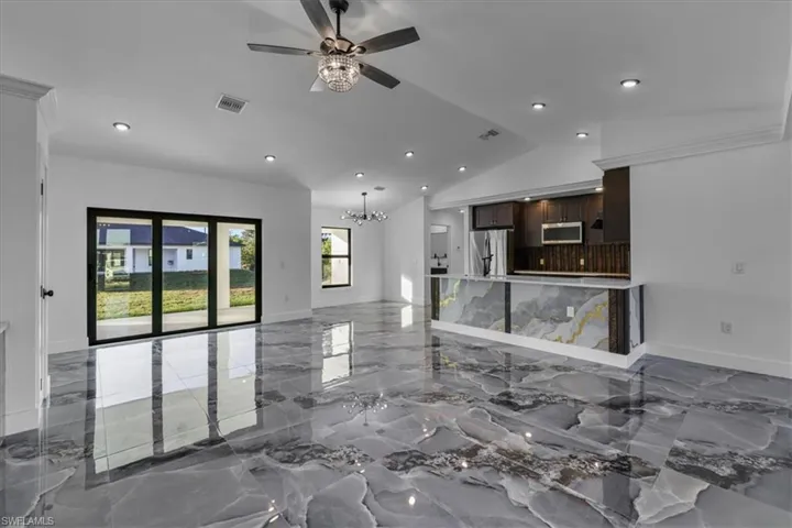 Living area with light marble finish floors, a chandelier, ceiling fan, recessed lighting, and vaulted ceiling