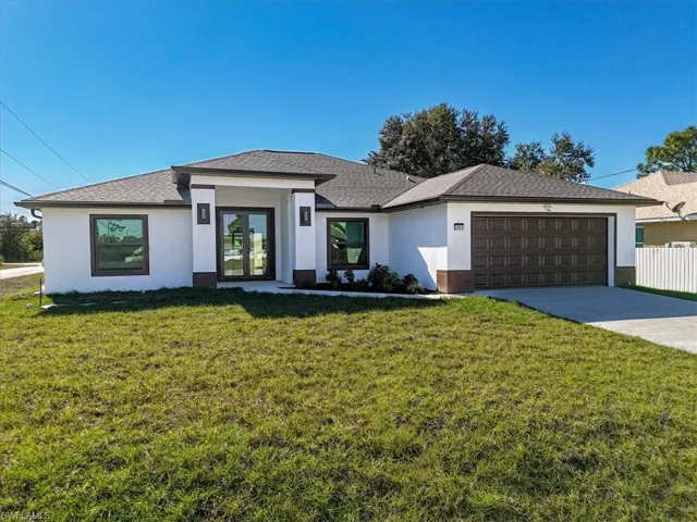 Prairie-style house with stucco siding, a front yard, concrete driveway, a shingled roof, and an attached garage
