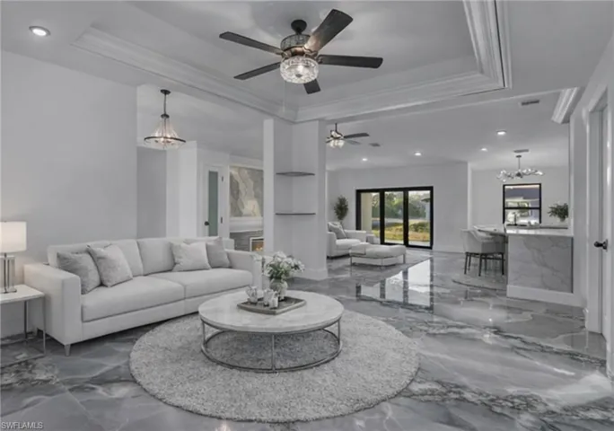 Living room featuring a chandelier, marble tiled flooring, recessed lighting, a tray ceiling, and ornamental molding