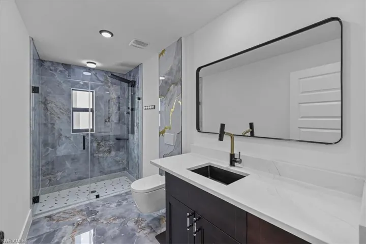 Bathroom with marble tiled floors, vanity, and a marble finish shower