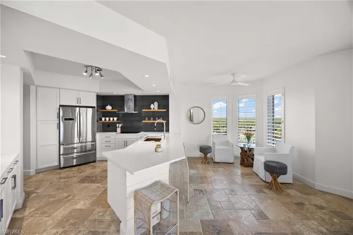 Kitchen with white cabinetry, stainless steel fridge, open shelves, a peninsula, and recessed lighting