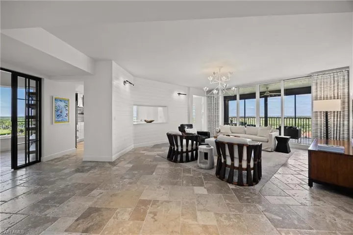 Living area with stone tile floors, a chandelier, and wood walls