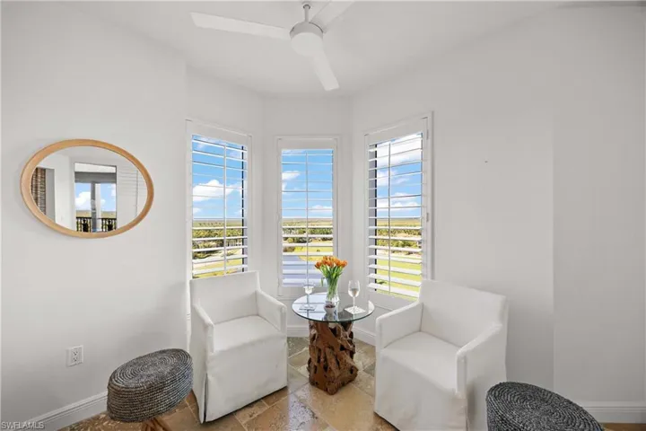 Living area with healthy amount of natural light, stone tile floors, and ceiling fan