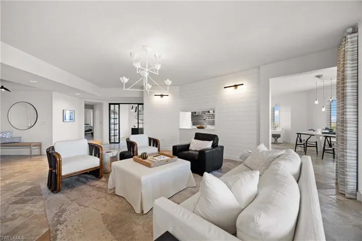 Living area with a chandelier, stone tile floors, wooden walls, and recessed lighting