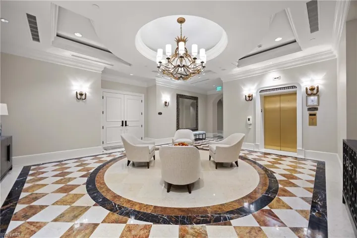 Dining space featuring a raised ceiling, a chandelier, crown molding, elevator, and arched walkways