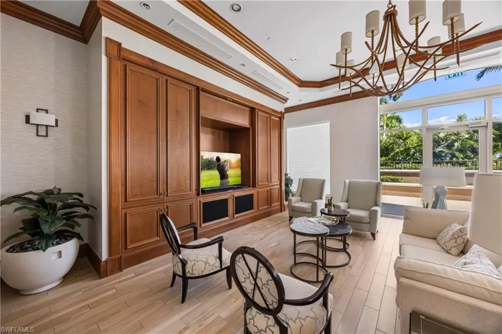 Living room featuring light wood-style floors, a chandelier, and crown molding